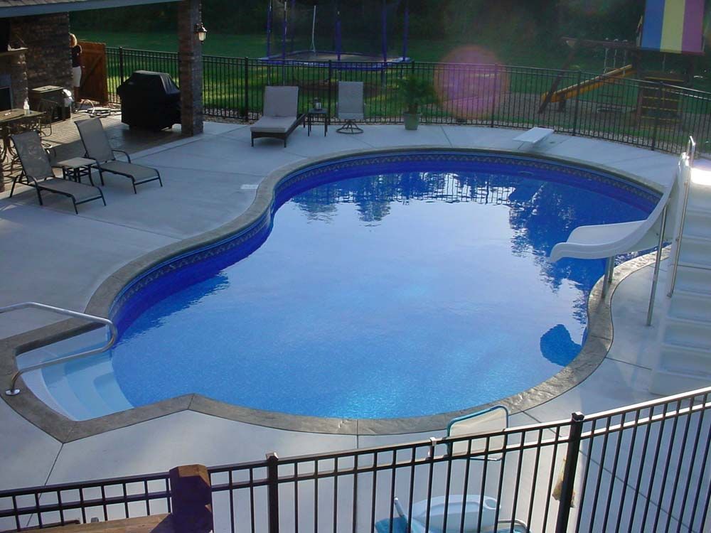 A large swimming pool surrounded by chairs and a fence