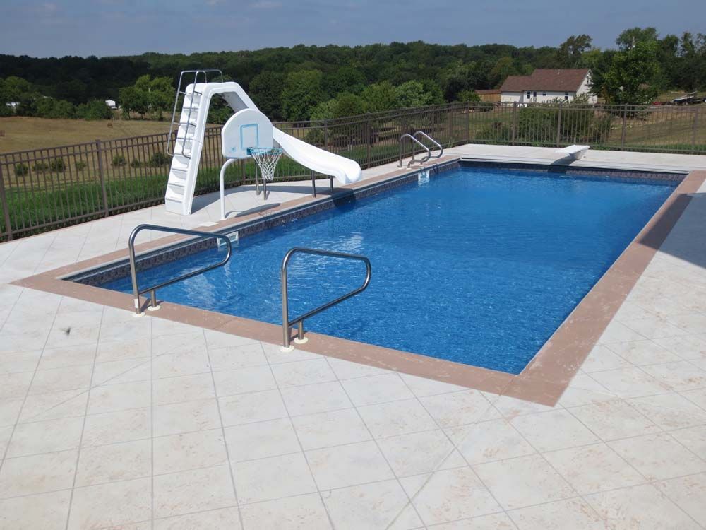 A large swimming pool with a slide and basketball hoop