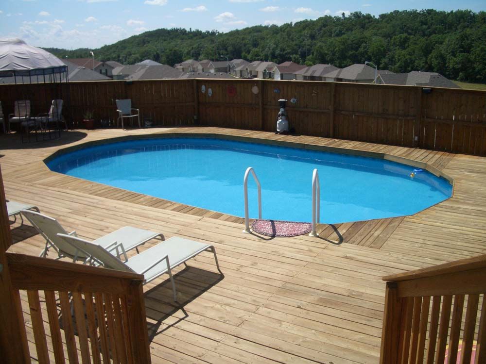 A large swimming pool is surrounded by a wooden deck
