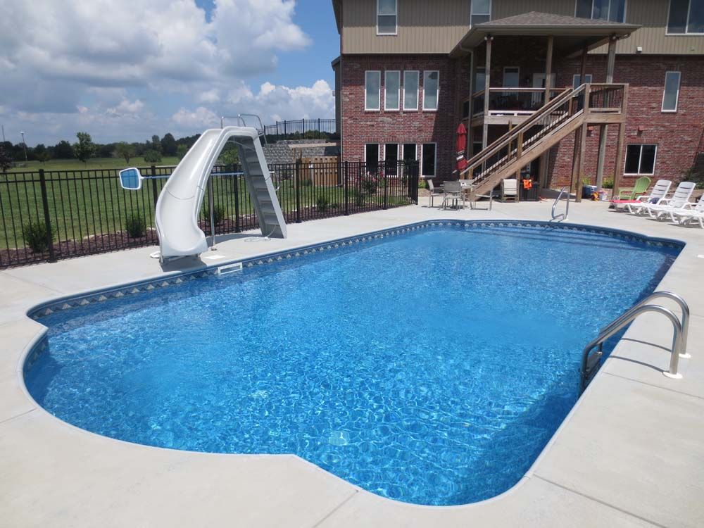 A large swimming pool with a slide in the backyard of a house