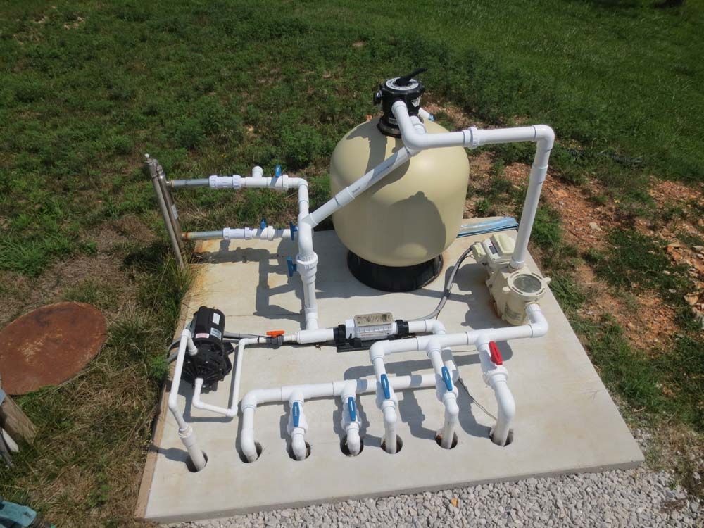 A swimming pool filter is sitting on top of a concrete platform