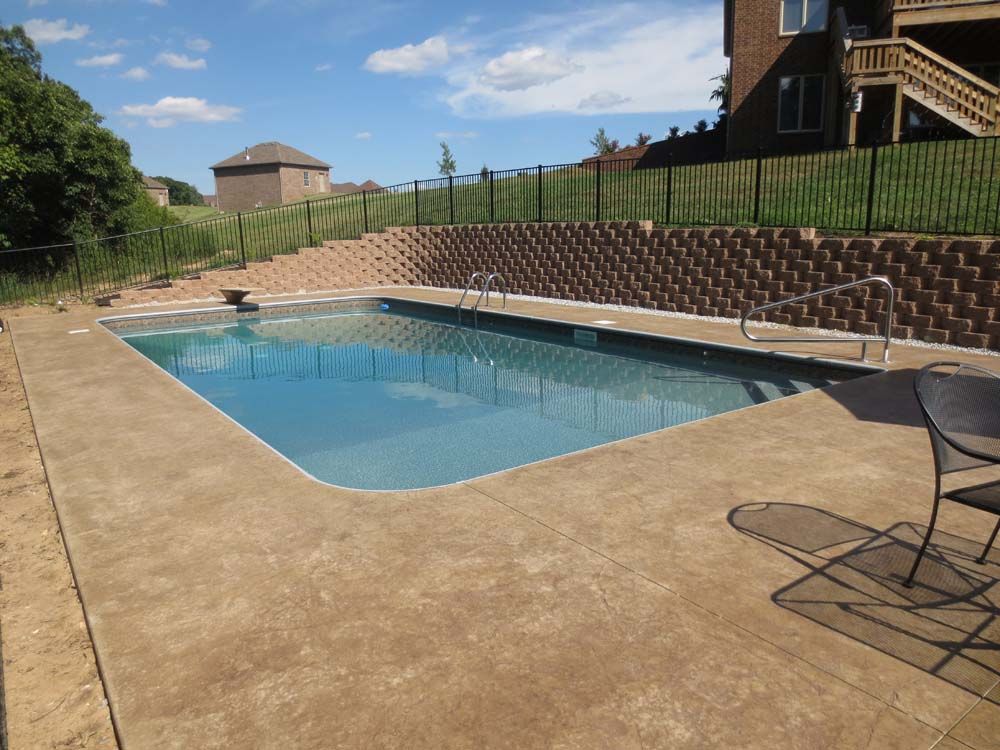 A large swimming pool is surrounded by a brick wall