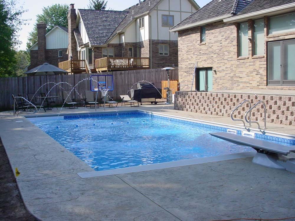 A large swimming pool in front of a brick house