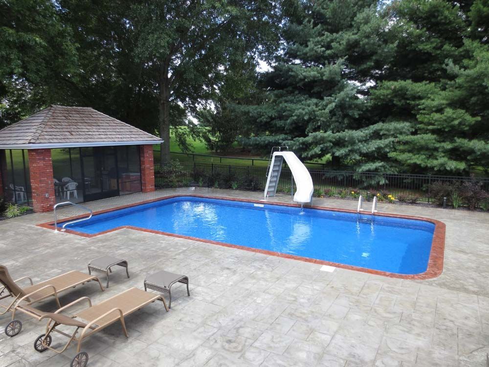 A large swimming pool with a slide in the backyard