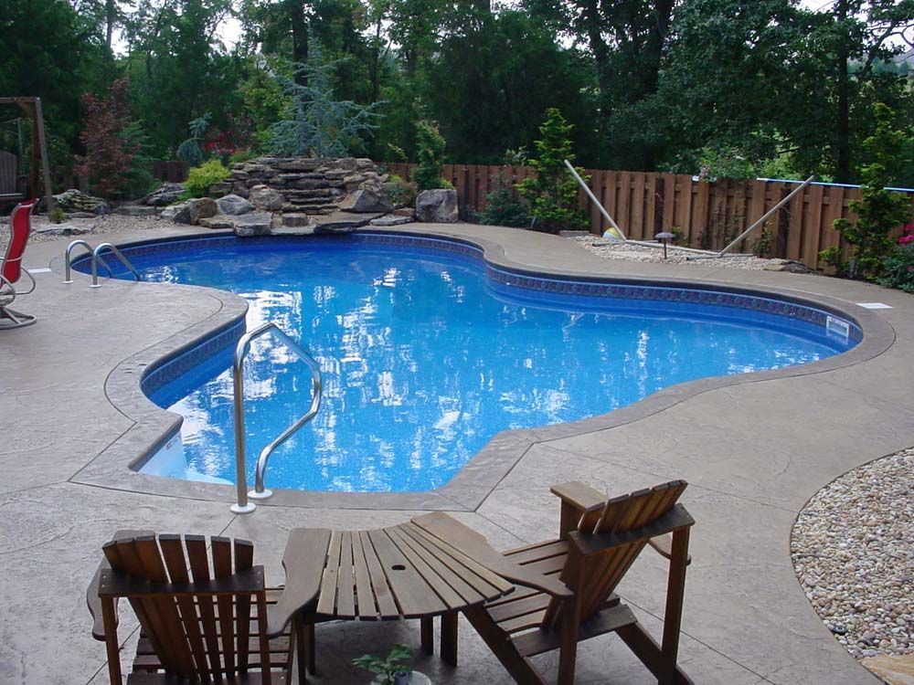A large swimming pool surrounded by chairs and a table