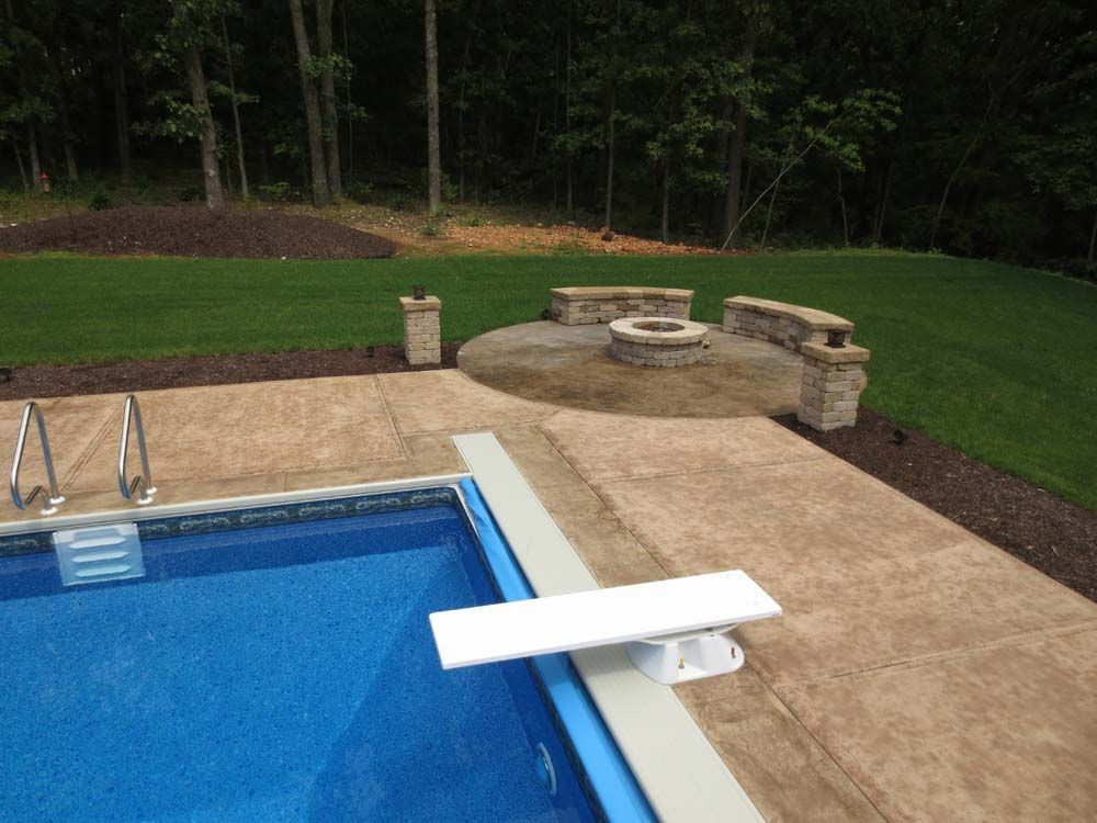 A swimming pool with a diving board and a fire pit