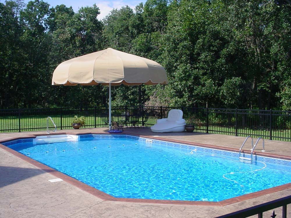 A large swimming pool with an umbrella and chairs