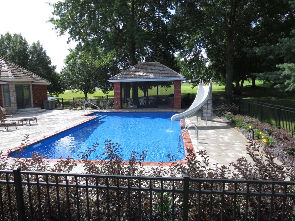 A large swimming pool with a slide and a gazebo in the background