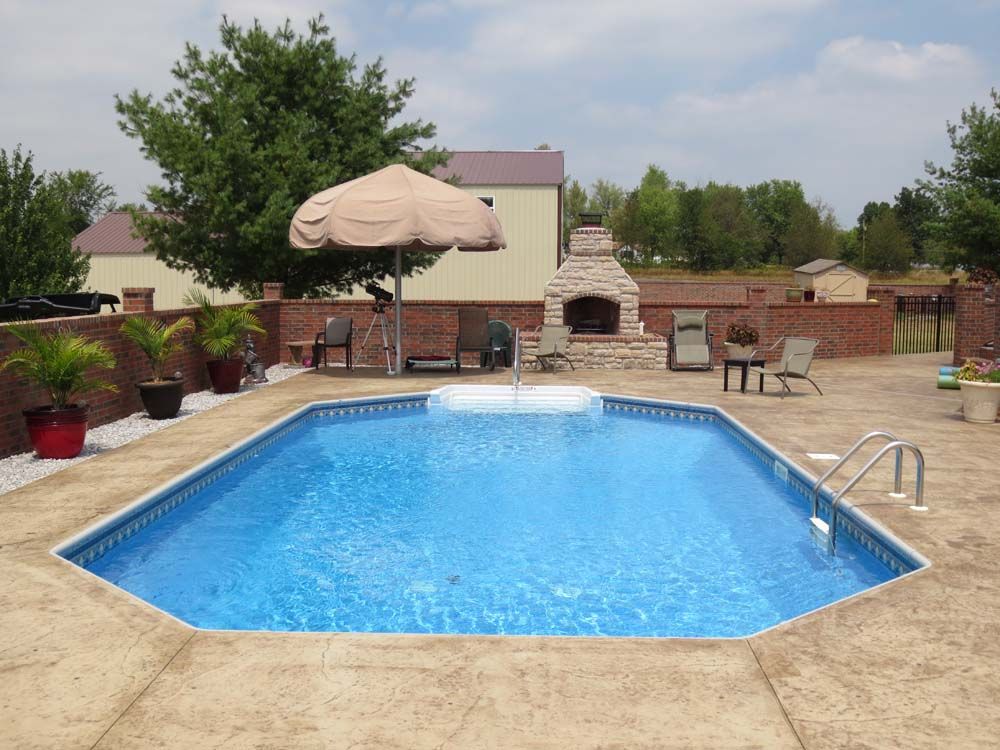 A large swimming pool with a fireplace in the background