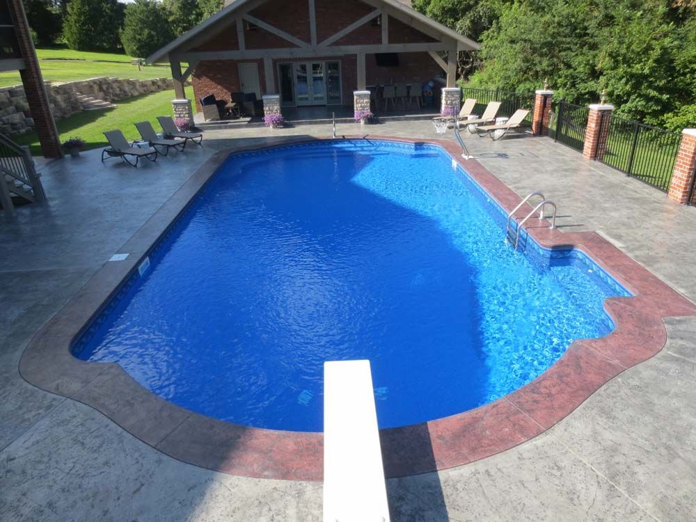 A large blue swimming pool with a diving board in the middle