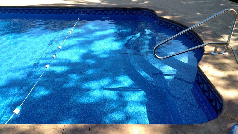 A blue swimming pool with a staircase leading to it.