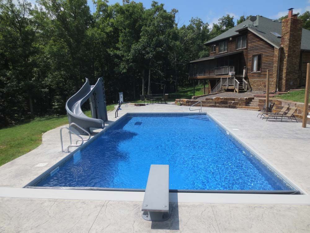 A large swimming pool with a slide and a house in the background