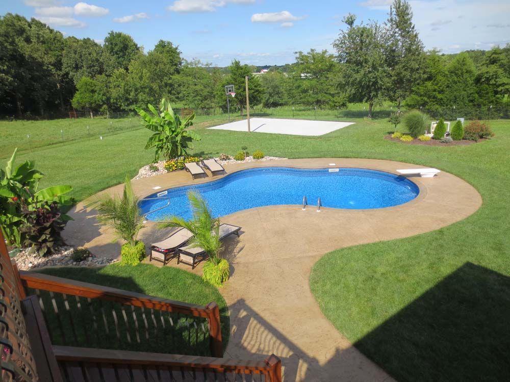 A large swimming pool in the middle of a lush green field