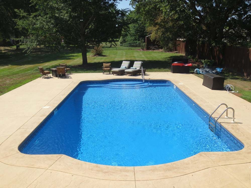 A large swimming pool surrounded by chairs and a table