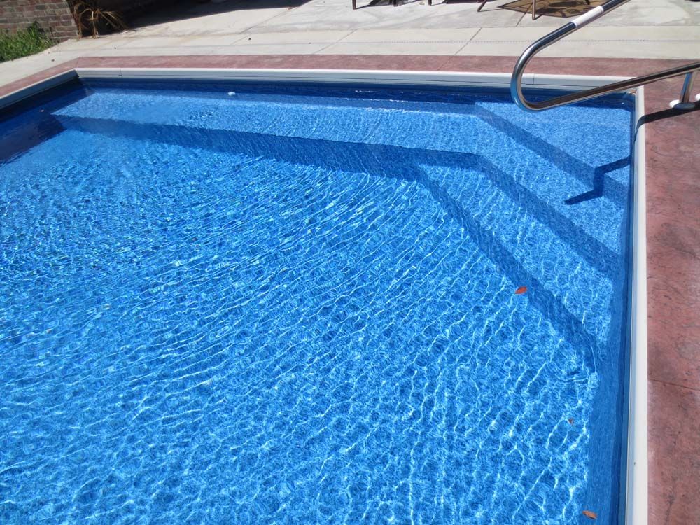 A large swimming pool with blue water and stairs