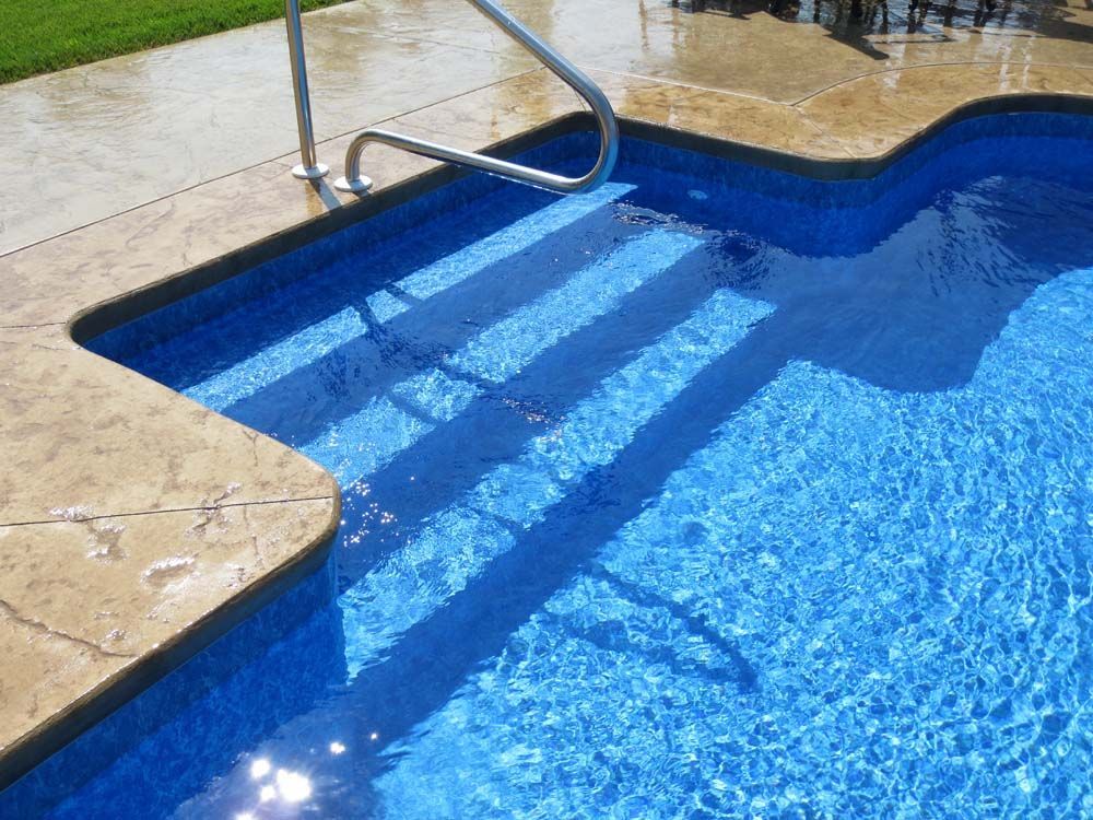 A swimming pool with blue water and stairs leading to it