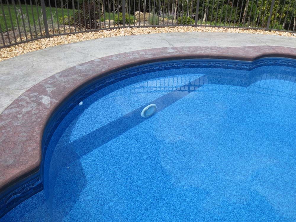 A blue swimming pool with a fence in the background.