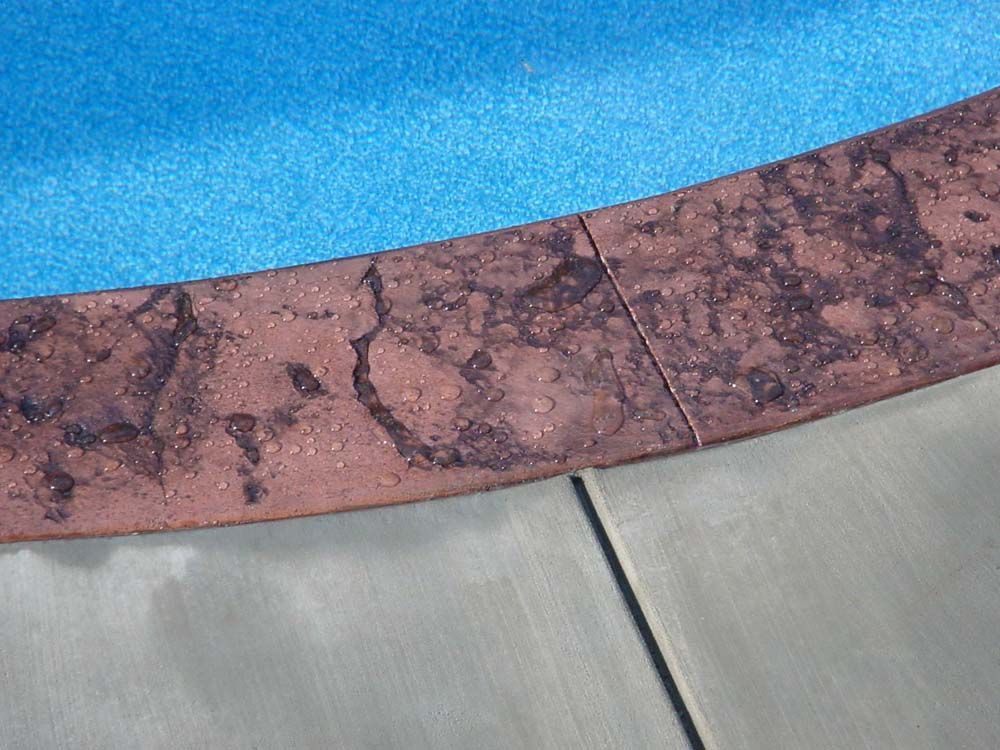 A close up of a concrete border around a swimming pool