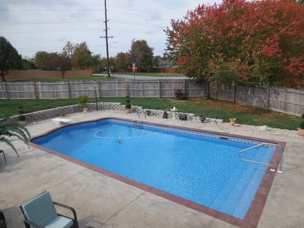 A large swimming pool in a backyard with a fence around it