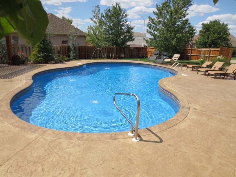 A large swimming pool surrounded by chairs and a fence