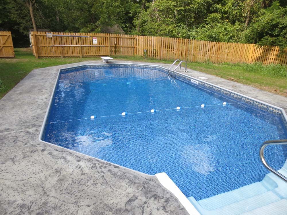 A large swimming pool with a wooden fence surrounding it