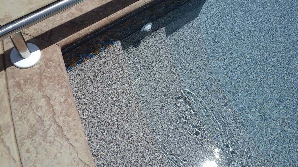 A close up of a swimming pool with stairs and a railing.