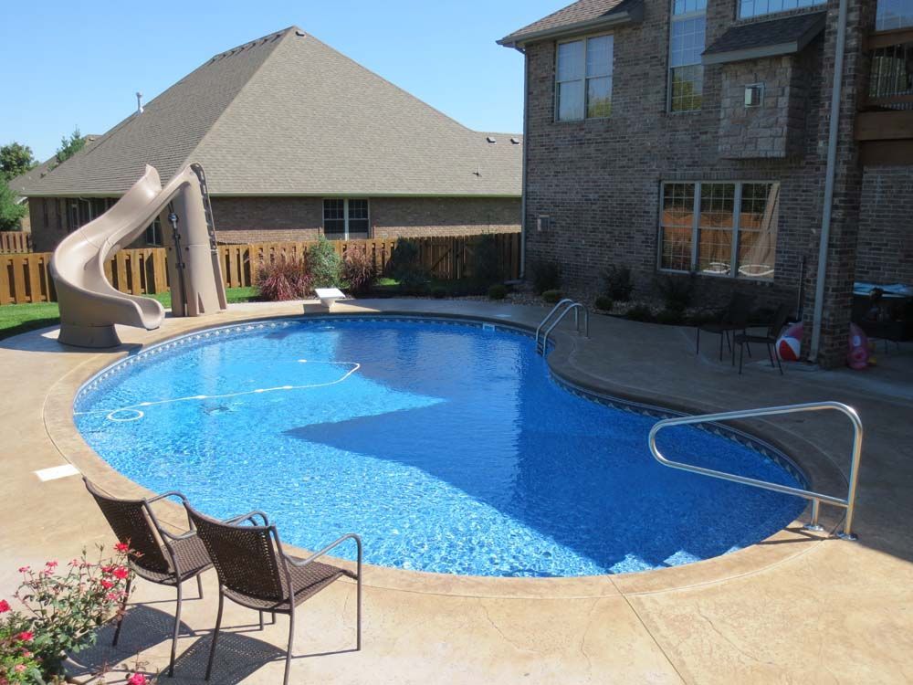 A large swimming pool with a slide in the backyard of a house