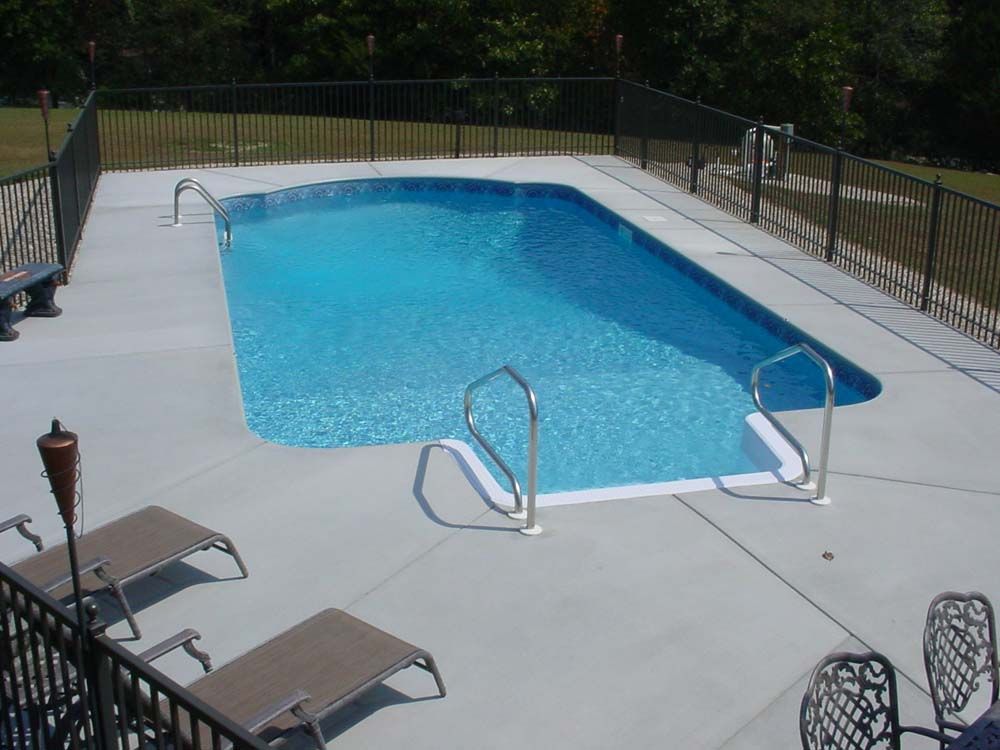 A large swimming pool surrounded by chairs and a fence