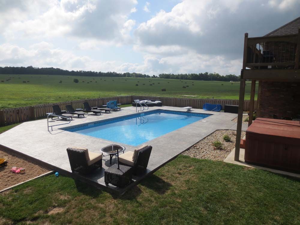 A large swimming pool surrounded by chairs and a hot tub