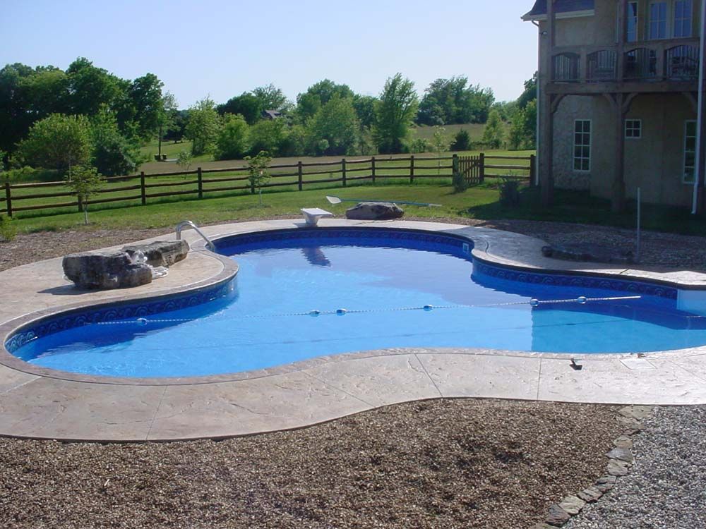 A large swimming pool with a house in the background