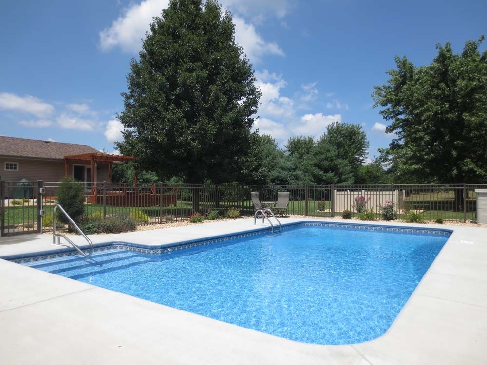 A large swimming pool surrounded by trees and a house