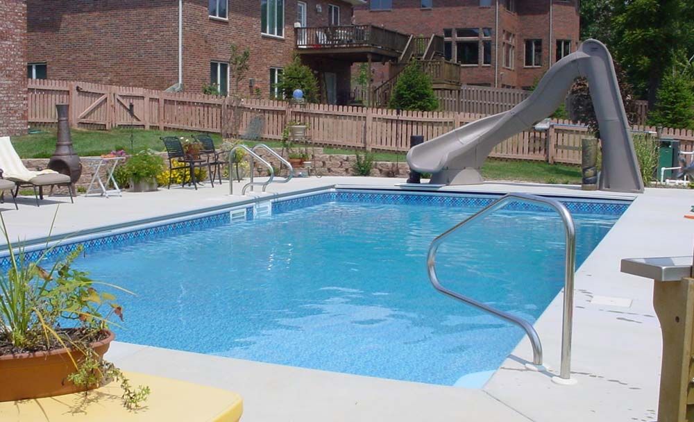 A large swimming pool with a slide in the backyard
