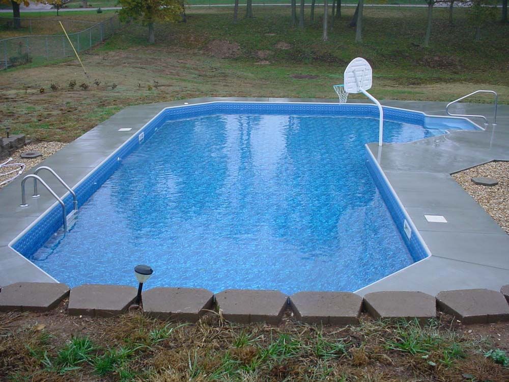 A large swimming pool with a basketball hoop in the backyard