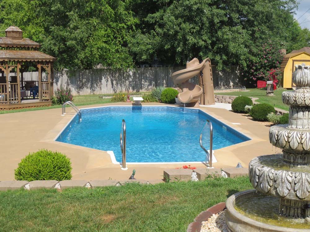 A large swimming pool with a slide and a gazebo in the background