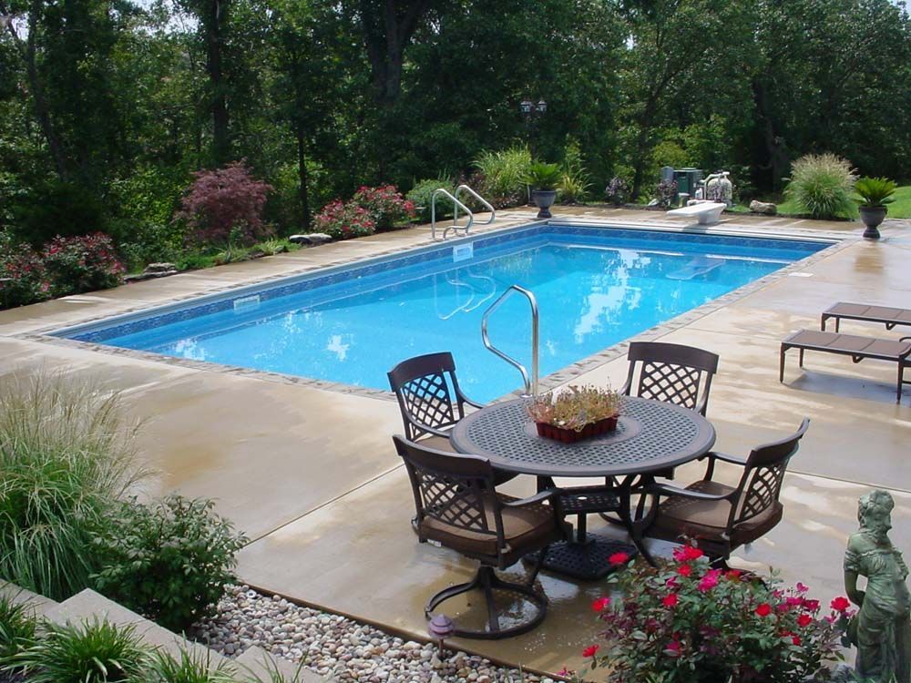 A large swimming pool with a table and chairs in front of it