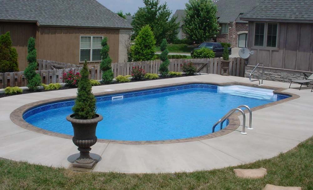 A large swimming pool in a backyard with a house in the background