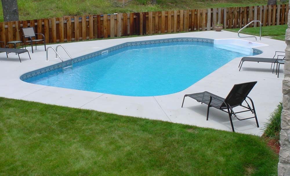 A large swimming pool surrounded by chairs and a wooden fence