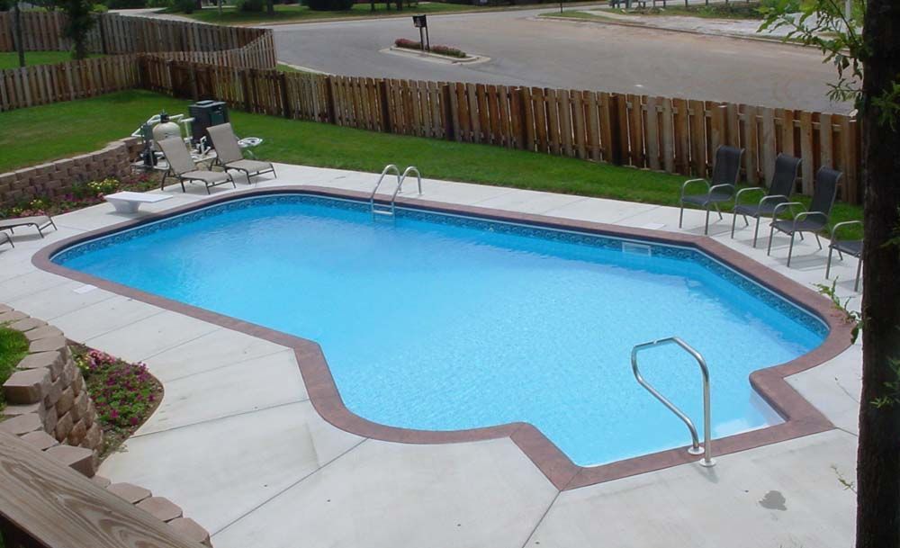 A large swimming pool is surrounded by chairs and a fence.