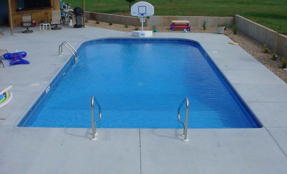 A swimming pool with a basketball hoop in the backyard