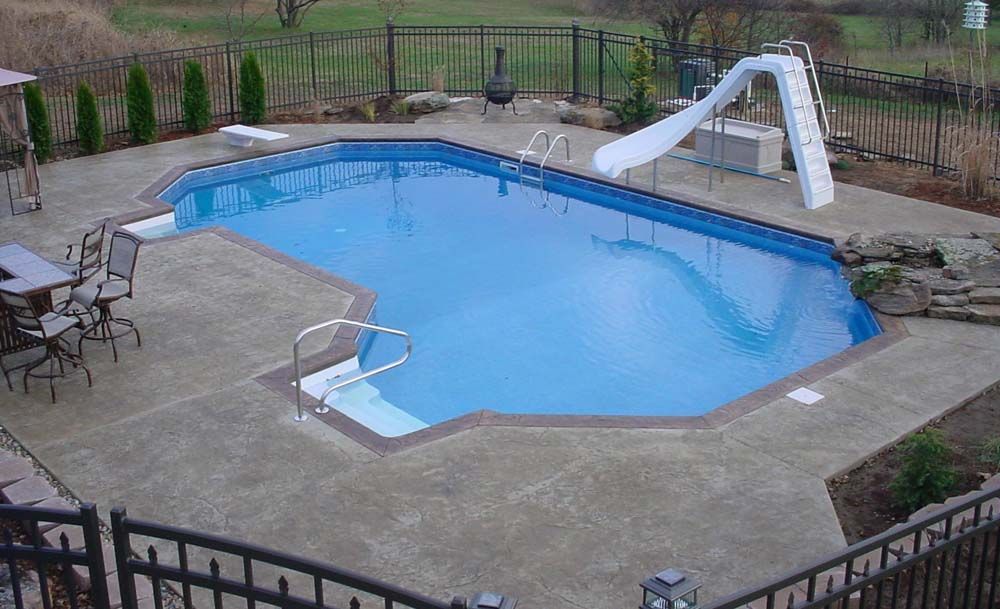 A large swimming pool with a slide in the backyard.