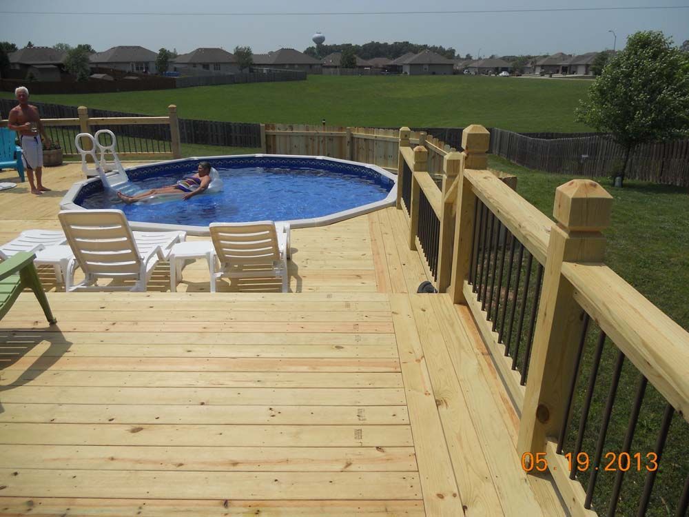 A wooden deck with a swimming pool in the backyard