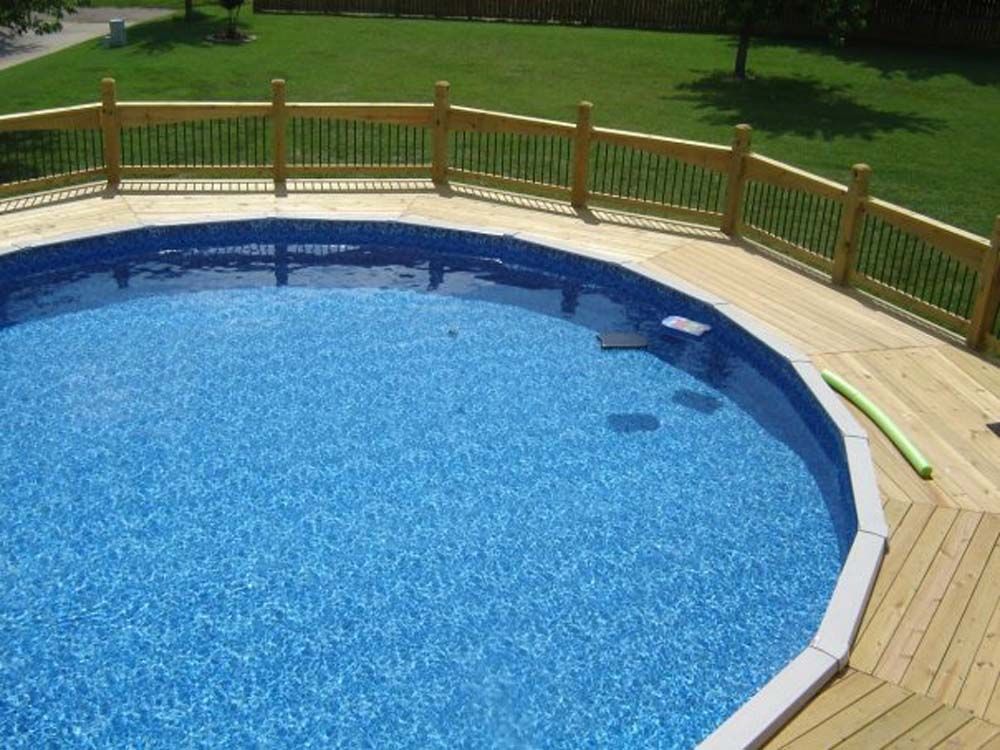 A swimming pool with a wooden deck and fence around it