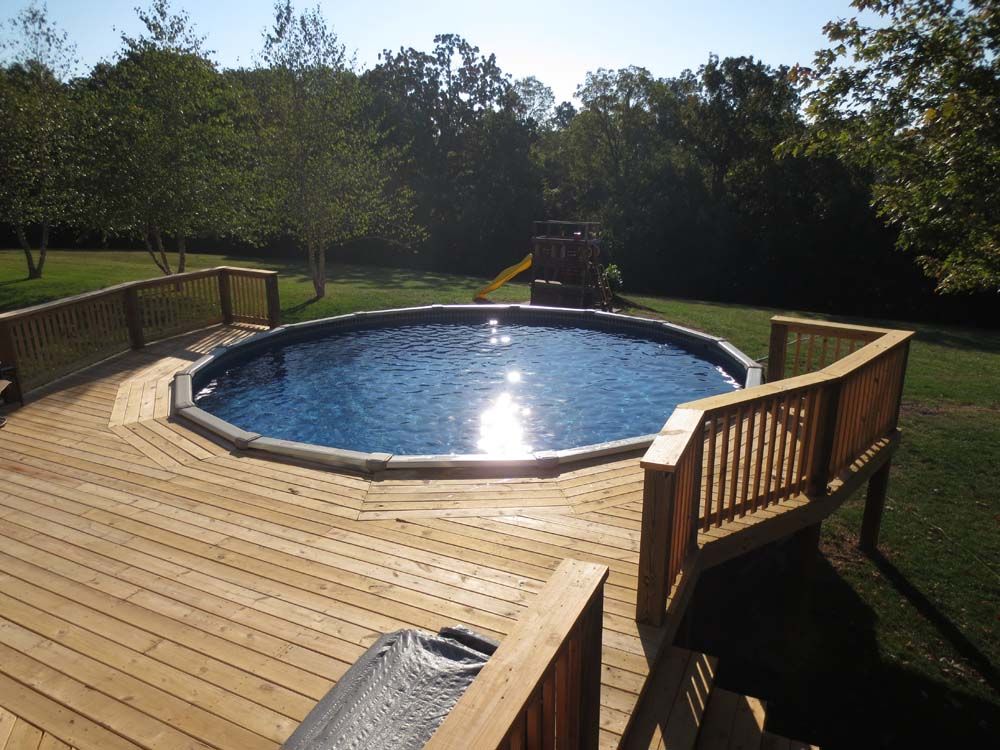 A large swimming pool is surrounded by a wooden deck