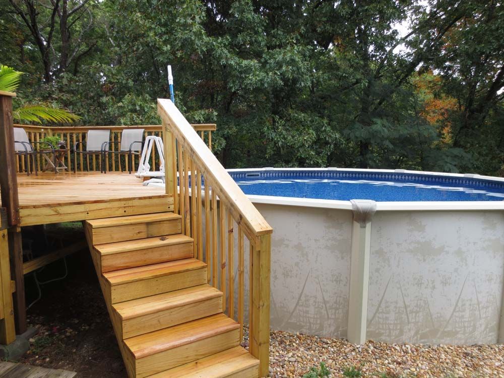 A wooden deck with stairs leading up to a pool