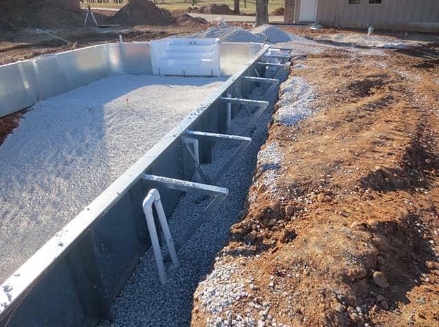 A swimming pool is being built in the dirt next to a house.