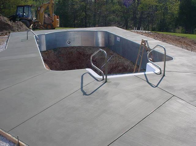 A swimming pool is being built with a concrete deck and stairs.