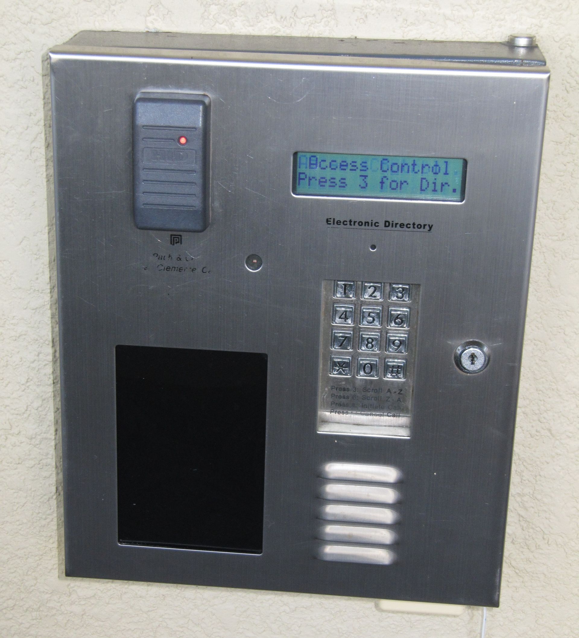 Stainless steel building intercom with keypad, display, speaker grill, and card reader.