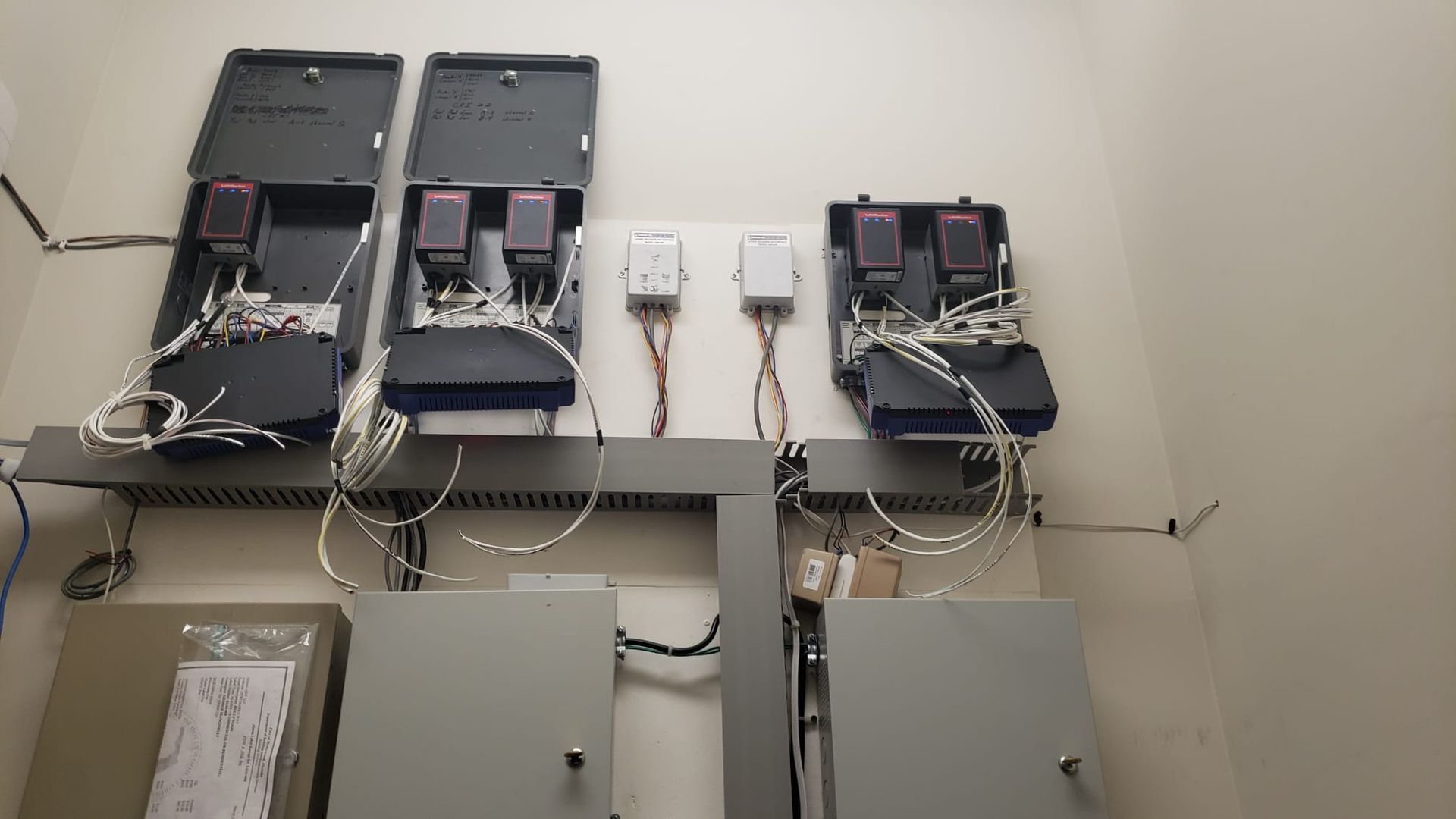 Open electrical panels and wiring mounted on a wall in a utility area.
