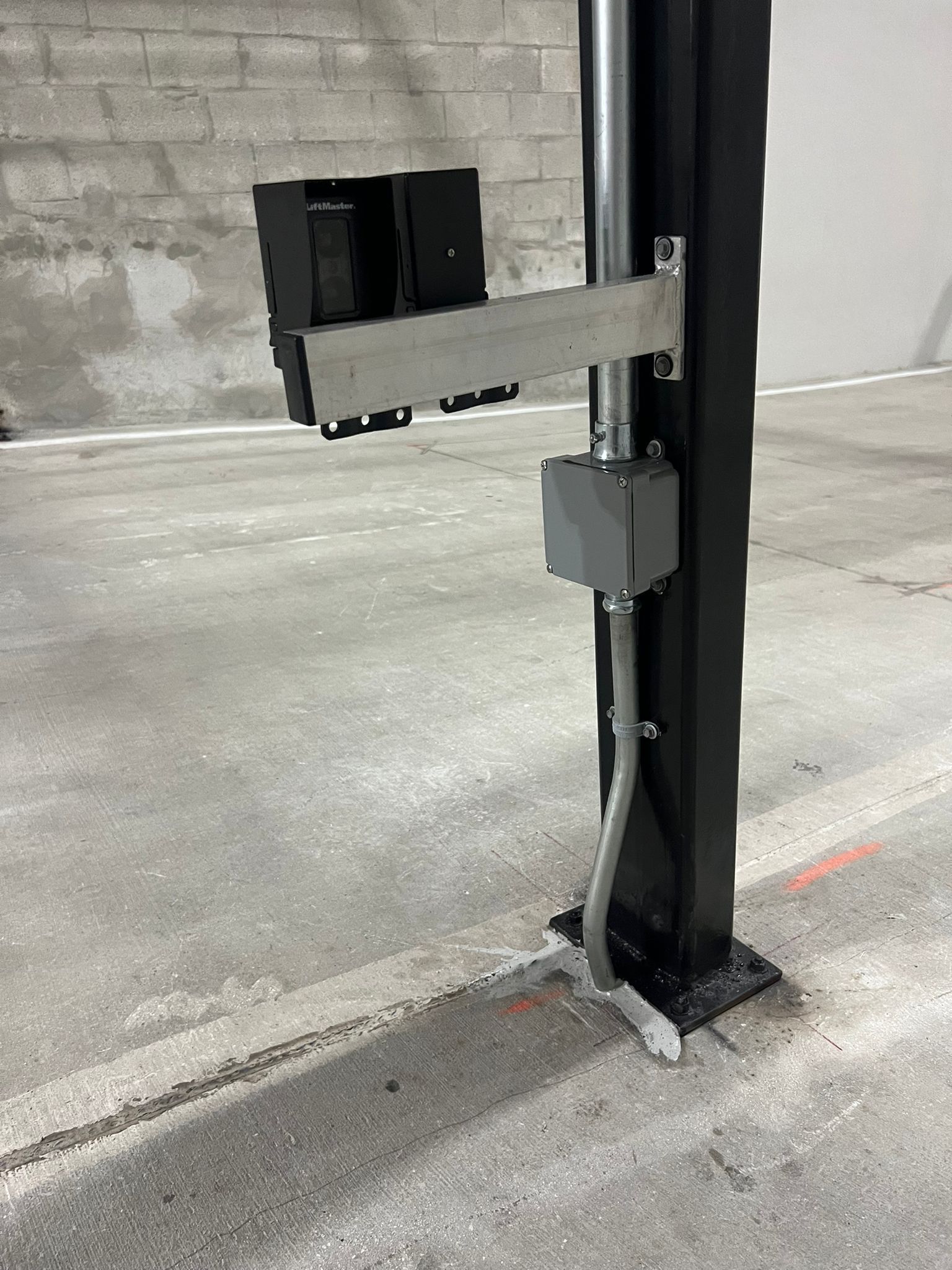 Black vertical lift post with extending arm mounted on a concrete floor in an industrial garage.