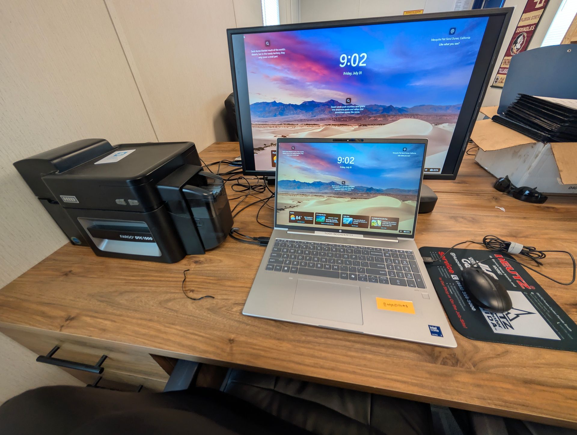 Desktop setup with printer, laptop, monitor, keyboard, and mouse on a wooden desk